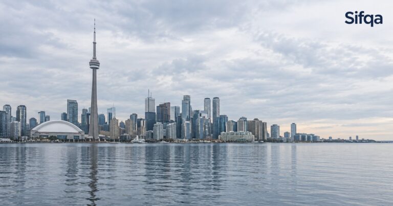 The Toronto skyline with the CN Tower seen across the water under a cloudy sky.