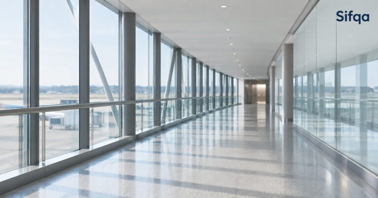 A bright, empty glass-walled airport walkway overlooking the apron and parked aircraft.