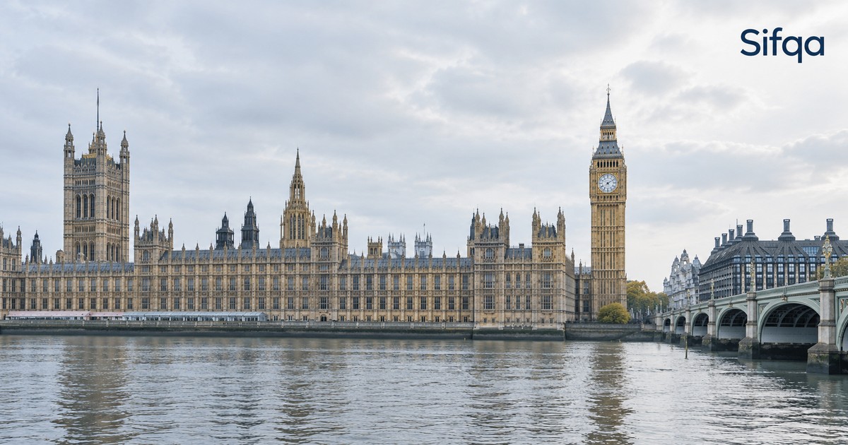 The Houses of Parliament and Big Ben seen across the River Thames in London under a pale sky.